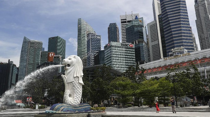 People are dwarfed against the financial skyline as they take photos of the Merlion statue along the Marina Bay area in Singapore, Tuesday, June 30, 2020. (AP Photo/Yong Teck Lim)
