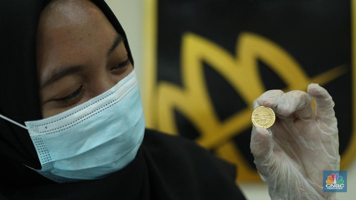 Petugas menunjukkan koin emas Dirham di Gerai Butik Emas Antam, Jakarta, Kamis (4/2/2021). Bank Indonesia (BI) mengajak masyarakat dan berbagai pihak untuk menjaga kedaulatan Rupiah sebagai mata uang NKRI. (CNBC Indonesia/ Tri Susislo)